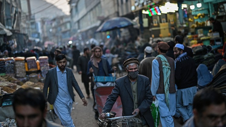 Afghan people walk through a street along a market in Kabul on October 28, 2021.
