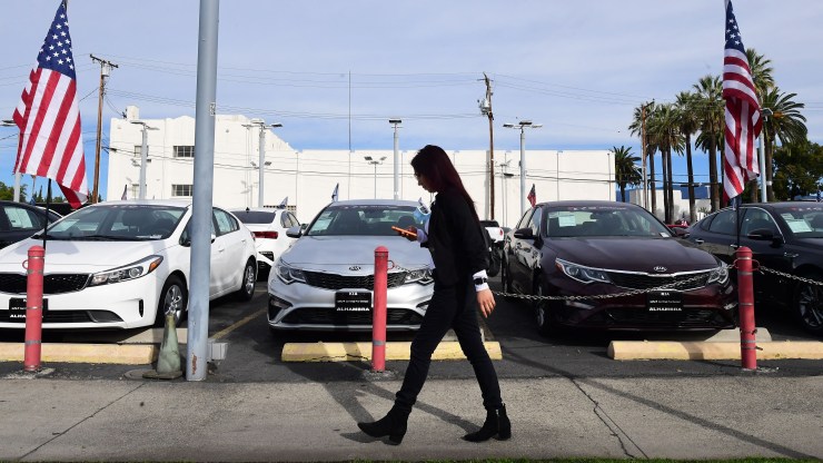 A pedestrian walks past a certified pre-owned car sales lot in Alhambra, California on January 12, 2022.