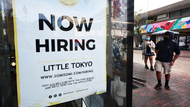 A "now hiring" sign is posted in the window of an ice cream shop in Los Angeles, California on January 28, 2022.