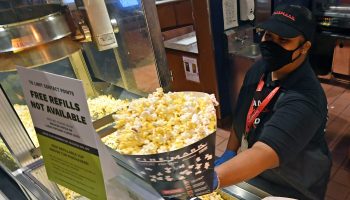 Movie theater employee handing a customer popcorn