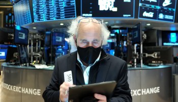 A masked trader works on the floor of the New York Stock Exchange.