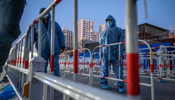 Health workers wearing protective garments help people arriving for COVID tests on Jan. 25 in Beijing.
