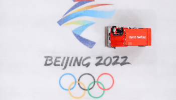 An ice resurfacing machine cleans the ice at the Capitol Stadium in Beijing. The machine can be seen on an ice rink with the phrase "Beijing 2022" above the symbol of Olympic rings.