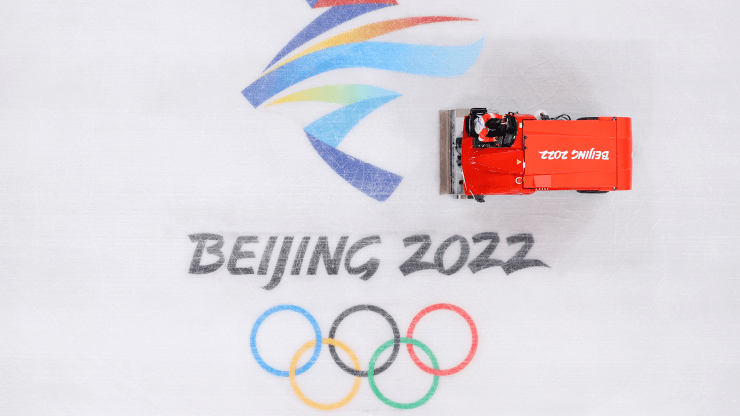 An ice resurfacing machine cleans the ice at the Capitol Stadium in Beijing. The machine can be seen on an ice rink with the phrase "Beijing 2022" above the symbol of Olympic rings.