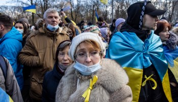People in Kyiv,Ukraine stand in a group as part of a public demonstration, as Ukrainian flags fly in the background. The scene is part of a Unity March to show solidarity and patriotic spirit over the escalating tensions with Russia.