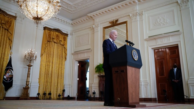 President Joe Biden stands at a podium in the East Room of the White House.