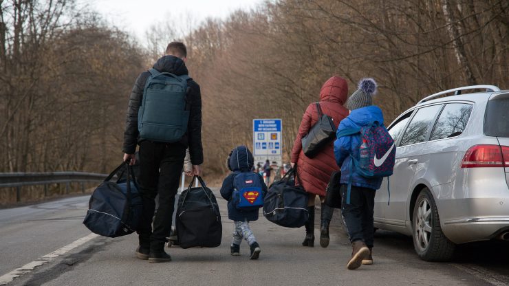 People carrying bags walk on the street after crossing the Slovak-Ukrainian international crossing border on Feb. 24 in Ubla, Slovakia.