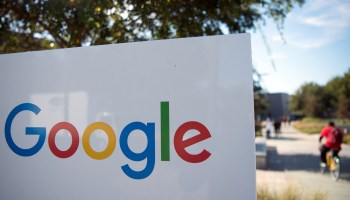 A man rides a bike past a Google sign in Mountainview, California.
