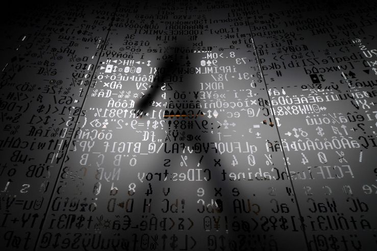 A person walks behind a glass wall with machine coding symbols.