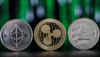 Three alternative currency coins -- ethereum, ripple and litecoin -- are positioned in front of a hazy green and black background.