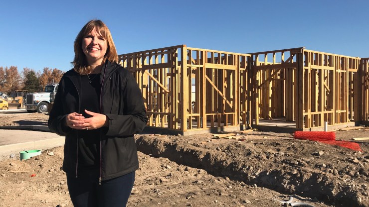 Roxanne DeCarlo, executive director for the Empowerment Center, stands in front of a semi-built affordable apartment complex.