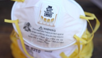 A stack of 3M white N95 masks with yellow straps.