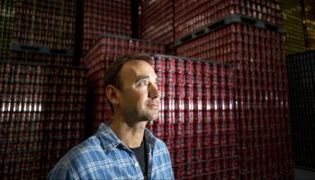 Denver Beer Co. founder Patrick Crawford stands before a mountain of cans inside his production facility in the city's Sunnyside neighborhood on Feb. 8.