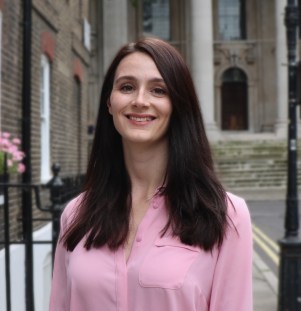 Danielle Boxall of the Taxpayers' Alliance smiles while wearing a pink shirt in front of a building facade.