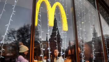 People look out a McDonald's restaurant window with the towers of the Kremlin reflected in it.