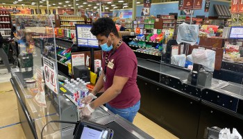 A checkout clerk works behind a plexiglass divider at the ShopRite Supermarket amid the coronavirus pandemic on April 24, 2020.