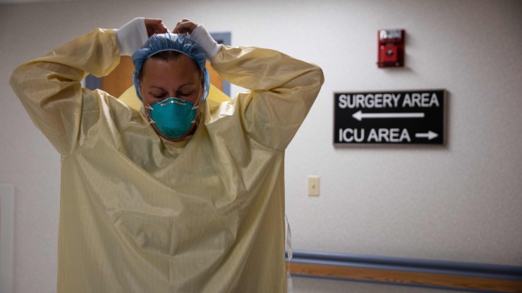 A health care worker suits up with personal protective equipment.