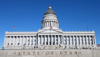 A landscape view of the Utah State Capitol in Salt Lake City, Utah. It features a plaque in front that says, "State of Utah."