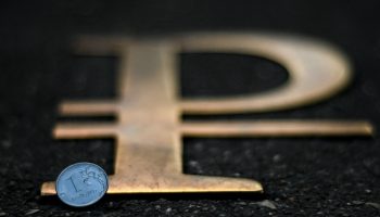 Russian ruble symbol with a ruble coin in front of it