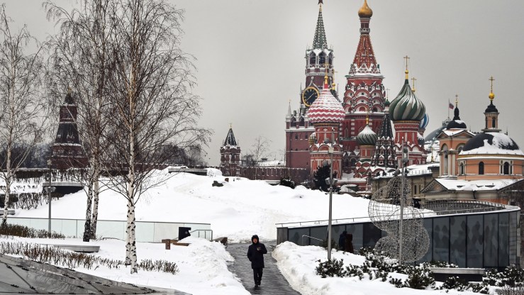 A man walks in front of the Kremlin's Spasskaya tower and St. Basil's cathedral in Moscow on February 3, 2022.