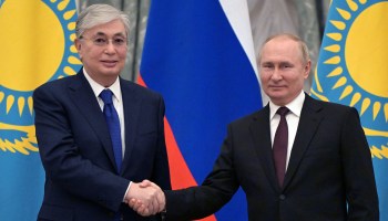 Kazakhstan President Kassym-Jomart Tokayev shakes hands with Russian President Vladimir Putin.
