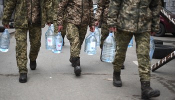 Ukrainian soldiers carry water supplies near a military base in Lviv.