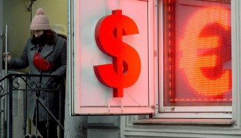 A woman leaves a currency exchange office displaying dollar and euro signs in St. Petersburg, Russia.