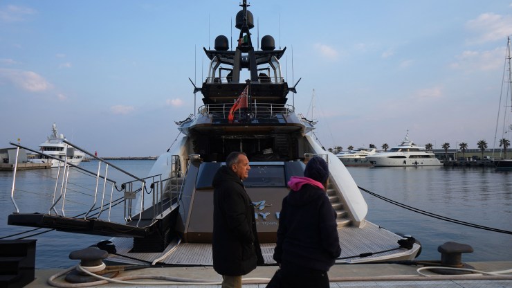 Pedestrians walk past the yacht "Lady M", owned by Russian oligarch Alexei Mordashov, docked at Imperia's harbor, on March 5, 2022. - Italian police seized the yacht on March 5, 2022 after the European Union targeted Mordashov and other Kremlin-linked oligarchs following Moscow's invasion of Ukraine. (Photo by Andrea BERNARDI / AFP) (Photo by ANDREA BERNARDI/AFP via Getty Images)