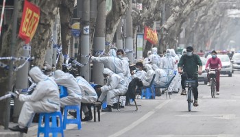 Workers are seen wearing protective clothes next to some lockdown areas after the detection of new cases of covid-19 in Shanghai on March 14, 2022