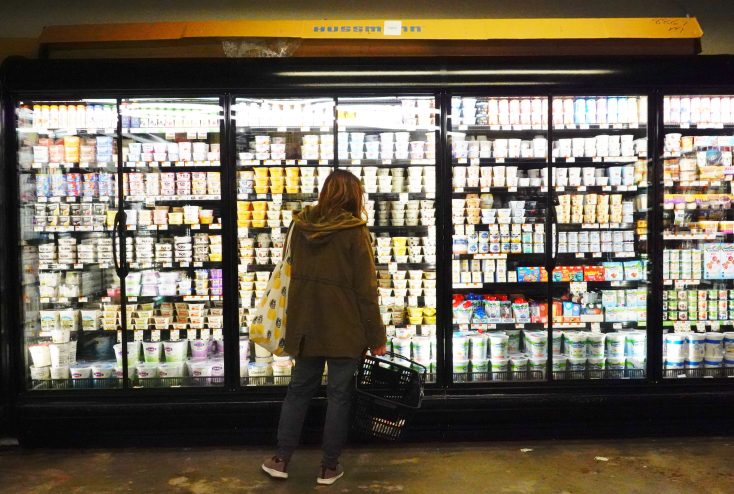 Image of a woman standing in front of the refrigerators at a grocery store