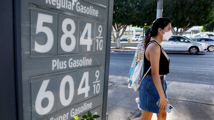 A pedestrian walks past a gas station advertising gas prices on March 25, 2022 in Los Angeles, California, with prices ranging from $5.84 to $6.04 per gallon.