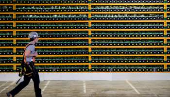 A construction worker walks past several bitcoin mining rigs.