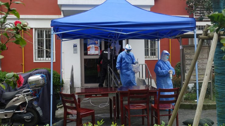 Medical workers in Shanghai exit a residential building that has been sealed. Shanghai has done mass testing in this latest surge of COVID-19 cases.