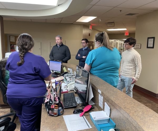 Dr. Beau Braden (left) and Kyle Kopec (right) of Braden Health speak with nurses gathered at the front desk of Houston County Community Hospital, which the company is taking over.