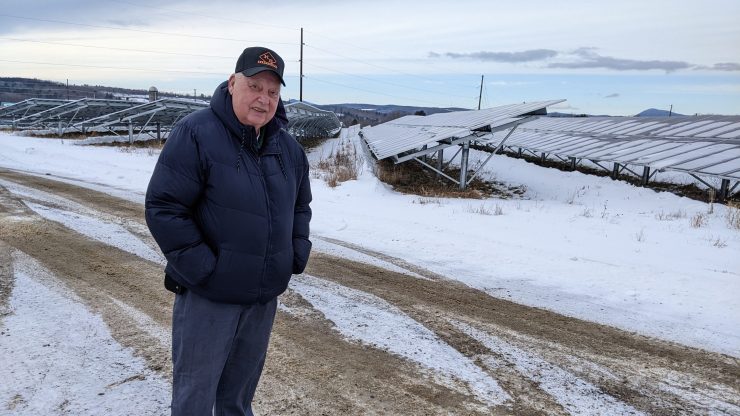 Farmer Bussie York stands amidst the large solar array of about 300,000 panels on his farm in Farmington, Maine.