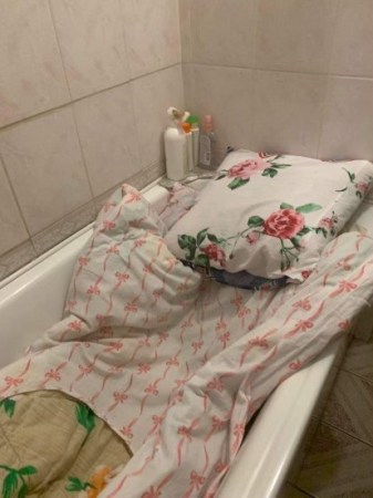 A bathtub filled with blankets and pillows served as a bed for Alla Mikhno in Kyiv during Russian bombing. 