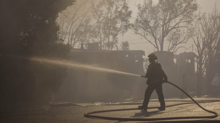 Firefighter extinguishing a fire on a smoggy road.