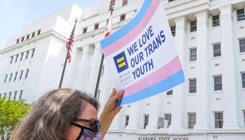 Woman holds a sign supporting trans youth outside the Alabama state house.