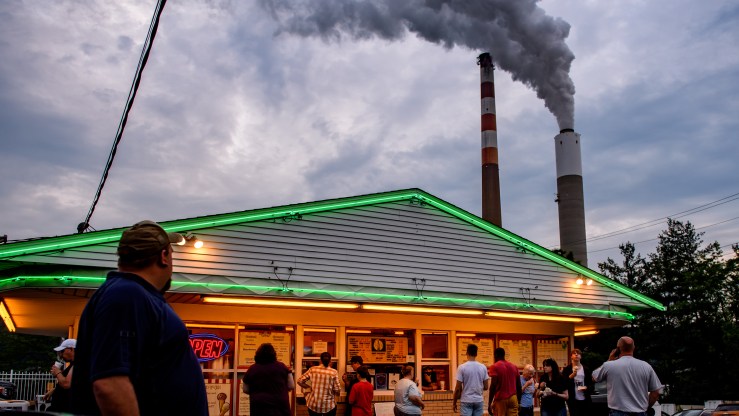 People line up for ice cream at Glens Custard in the shadow of GenOns Cheswick Power Station, which still burns coal to produce 637 megawatts of electricity for the region on June 7, 2021 about 15 miles northeast of Pittsburgh in Cheswick, Pennsylvania.