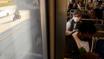 Transit passengers wear face masks as they ride the Metro C Line, formerly Green Line, light rail train alongside the 105 Freeway during rush hour traffic in Los Angeles, California on July 16, 2021.