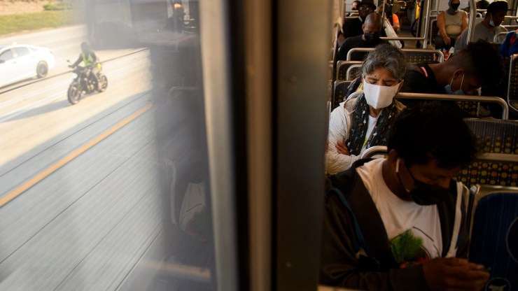Transit passengers wear face masks as they ride the Metro C Line, formerly Green Line, light rail train alongside the 105 Freeway during rush hour traffic in Los Angeles, California on July 16, 2021.