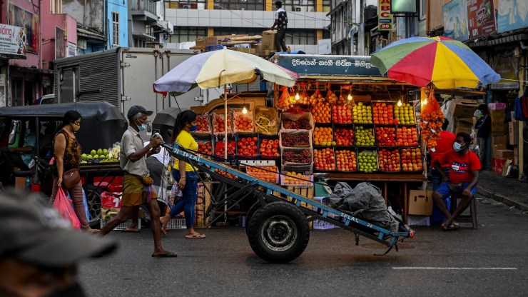 A fruit vendor (R) waits for customers in Colombo on October 28, 2021.