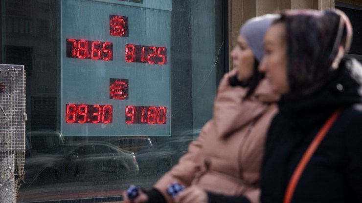 Women walk past a board showing currency exchange rates of the U.S. dollar and the euro against Russian ruble in Moscow on Feb. 22.