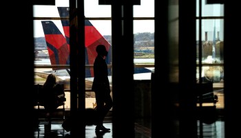 Delta Airlines aircrafts are seen in the background behind travelers passing through Ronald Reagan Washington National Airport in Arlington, Virginia on April 11, 2022.