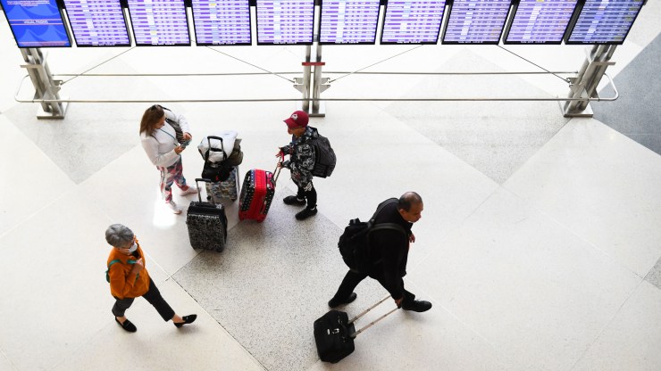 Airline passengers, some not wearing face masks following the end of Covid-19 public transportation rules, walk to flights in the airport terminal in Denver, Colorado on April 19, 2022.