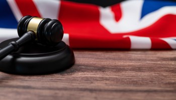 A wooden gavel with a British flag in the background.