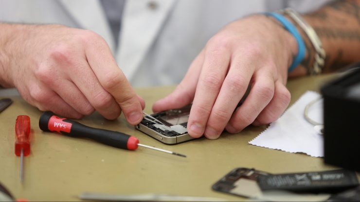 A pair of hands repair an iPhone.