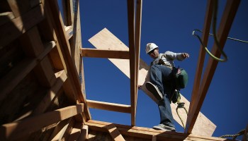 A worker carries lumber as he builds a new home.