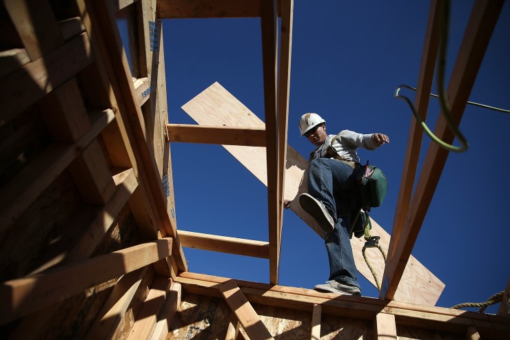 A worker carries lumber as he builds a new home.