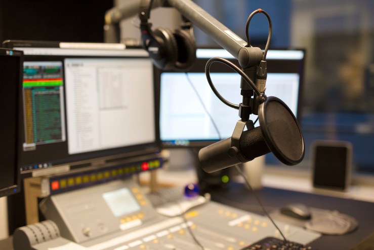 A microphone in front of the sound mixer and computers in a broadcasting radio studio.